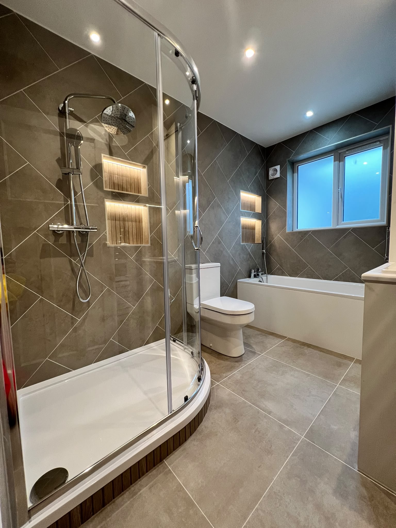 Luxury bathroom renovation with walk-in shower and rose tile feature wall